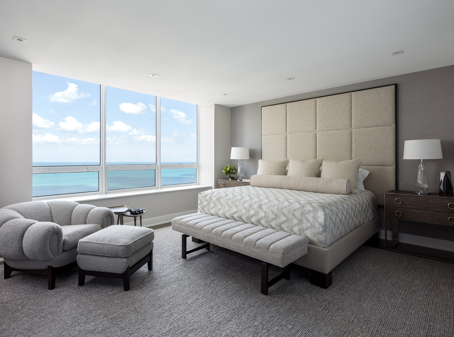 high rise bedroom with upholstered head board and view over lake